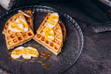 Waffles with bananas on a concrete gray background.