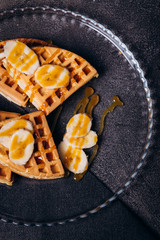 Waffles with bananas on a concrete gray background.