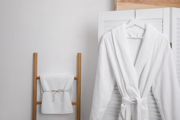 Hanger with clean soft bathrobe on screen - obrazy, fototapety, plakaty