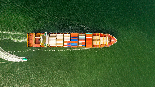 Aerial veaw a Large container ship is leaving the port full loaded with containers and cargo.