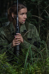 Portrait of beautiful army girl, soldier woman with rifle with optical sight and military uniform in the forest