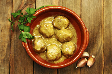 Meatballs in sauce, in casserole on wood