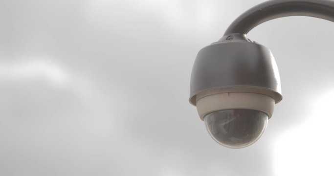 Footage of a surveilence cam on a building with clouds goiong fast in the background