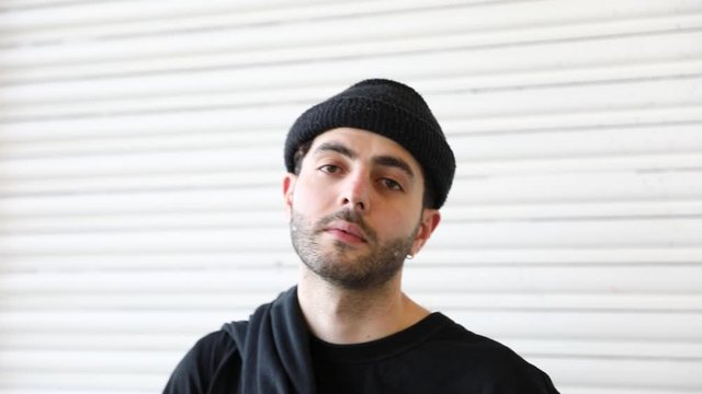 Portrait of bearded young man with cap on his head looking into the camera with pride in slow motion