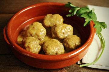 Meatballs in sauce, in casserole on wood