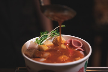 Pour spicy sauce into Delicious shabu put in paper bowl with many meatball different shape in Japanese style - Vertical photo