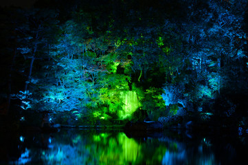 緑にライトアップされた滝と池