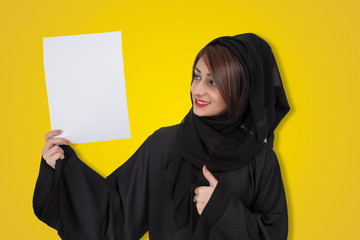 Your text here. Pretty young excited Arab woman holding empty blank board. Colorful studio portrait with yellow background.