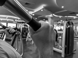 Closeup of man's hands while lifting weight in a gym and doing the bodybuilding and increasing strength in black and white