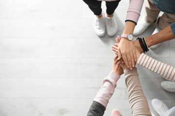 People holding hands together over light wooden background, top view with space for text. Unity...
