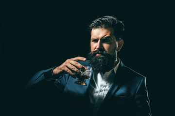 Bearded and glass of whiskey. Man Bartender with beard holds glass brandy. Alcohol concept. Stylish elegant bearded man Bartender holds whiskey glass.