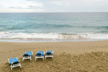 Fototapeta na wymiar Four empty sun loungers stand on the ocean. plastic trash is scattered around. environmental protection concept