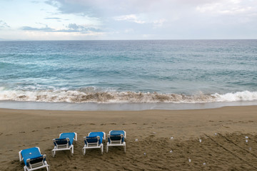 Four empty sun loungers stand on the ocean. plastic trash is scattered around. environmental protection concept