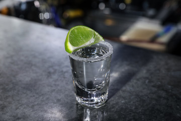 Mexican Tequila shot with lime slice on bar counter