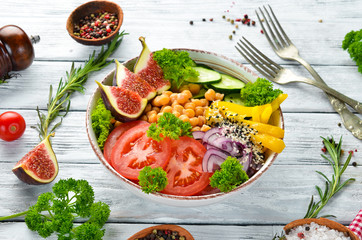 Healthy vegetable buddha bowl lunch with chickpeas, figs, cucumber, tomatoes and onions. Dishes menu. Free copy space. Top view.