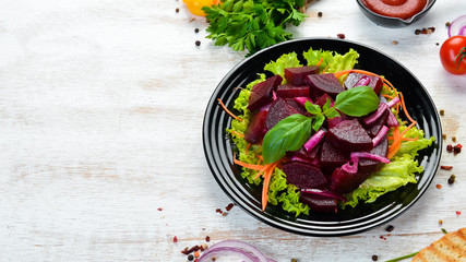 Beet salad with onions in a black plate on a white wooden background. Top view. Free space for your text.