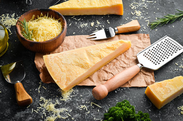 Piece of Parmesan cheese and cheese knife. On a stone background. Traditional Italian cheese. Top view. Free space for your text. - obrazy, fototapety, plakaty