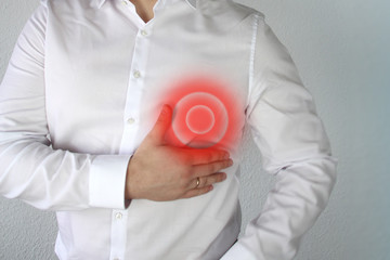 man in a white shirt holds on to the chest in the heart, a red circle, a symbol of throbbing pain,...