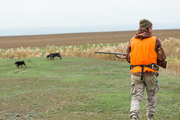 Hunting period, autumn season open. A hunter with a gun in his hands in hunting clothes in the...
