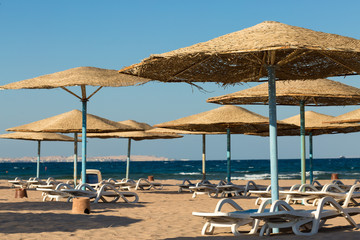 Beach umbrellas on the coastline of the sea at sunset.