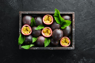Fresh passion fruit with leaves in Wooden Box. Tropical Fruits. Top view. Free space for text.
