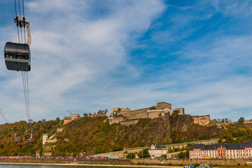 Nice panoramic view of the famous Ehrenbreitstein Fortress on the east bank of the Rhine with a close-up view of the cableway crossing the river in Koblenz, Germany on a fine autumn day with blue sky.