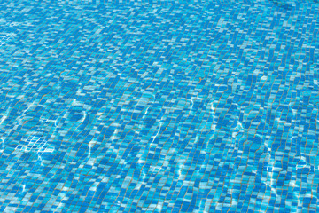 Surface of the pool, waves. The structure of blue tiles through the water.