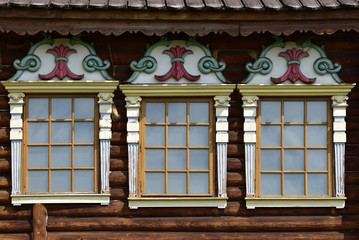 Three small framed windows in a dark wooden wall