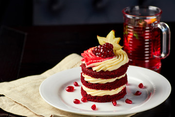 Cake Red Velvet with pomegranate and carambola, served with glass of fruit tea.