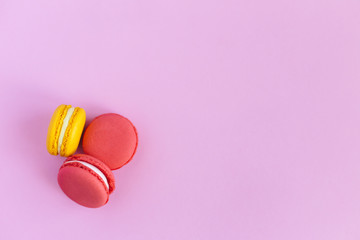Three tasty french macarons on pink background. Pink and yellow macarons.