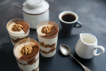 Tiramisu. Sponge cake with cream. Cup of coffee and tiramisu on a dark background.