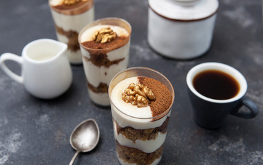 Tiramisu. Sponge cake with cream. Cup of coffee and tiramisu on a dark background.