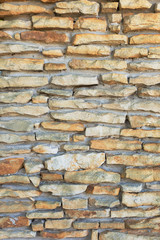 Part of a wall made of fine natural processed stone. Beautiful stone background. Close up. The texture of the wall is made of thin natural stones stacked on top of one another. 