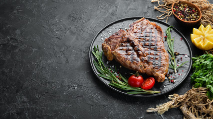 Grilled T-bone steak with rosemary and spices. On an old background. Top view. Free copy space.