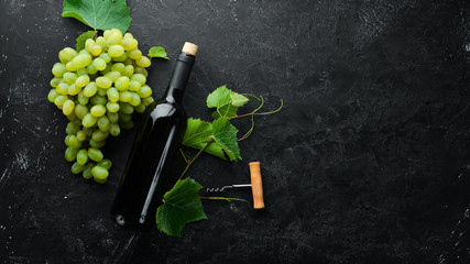 Red wine and fresh grapes on a black stone table. Top view. Free space for your text.