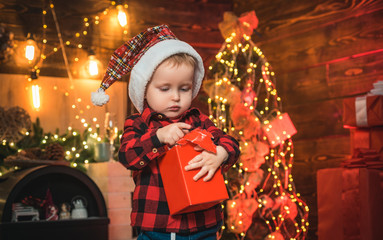Fototapeta na wymiar Little baby with Christmas gift in his hands on the Christmas background. Christmas tree. Happy kid.