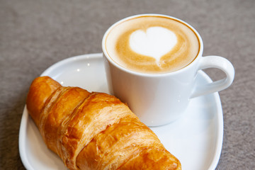 Latte art hot coffee with fresh baked butter croissant