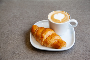 Latte art hot coffee with fresh baked butter croissant