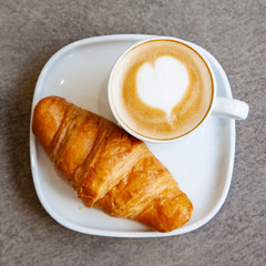 Latte art hot coffee with fresh baked butter croissant
