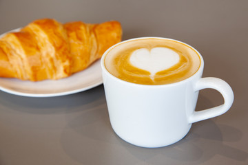 Latte art hot coffee with fresh baked butter croissant