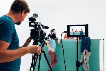 professional camera operator filming video with three actors in the studio