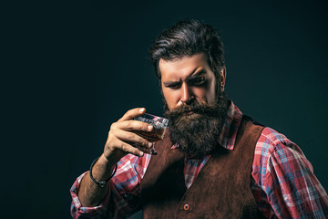 Man Bartender holding glass of whisky. Man or businessman drinks whiskey on black background. Degustation and tasting.