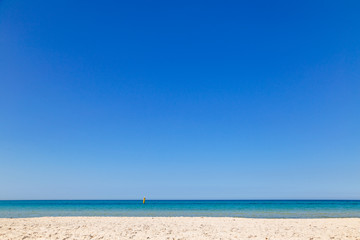 Fototapeta na wymiar Clear blue sky, calm sea water and soft yellow sand. Horizontal color photography.