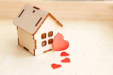 Obraz na płótnie Canvas Miniature toy model house with red heart on wooden backdrop. Eco Village abstract environmental background. Real estate mortgage property insurance sweet dream home ecology concept