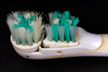 Worn electric toothbrush head against a black background