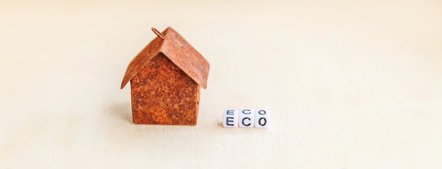 Miniature toy model house with inscription ECO letters word on wooden backdrop. Eco Village, abstract environmental background. Ecology zero waste social responsibility recycle bio home concept Banner