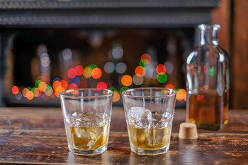 the waiter pours whiskey in a bar on a wooden table in an old-fashioned glass