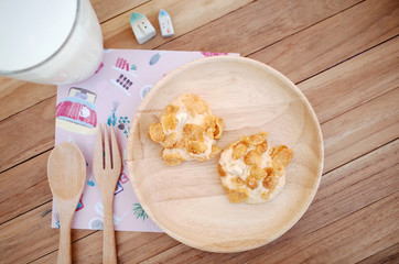 Homemade Two Cookies Cornflakes on wooden plate with fork and spoon with fresh milk                                                                
