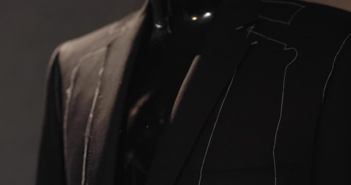 A tailor is proudly touching a customers suit which is soon to be finished