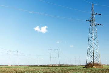 High voltage power lines running through agricultural fields in flat-lands on a clear sunny late winter day